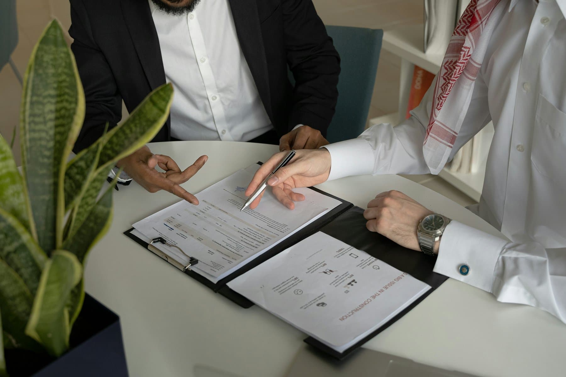 Two people reviewing a printed contract at a table with a pen