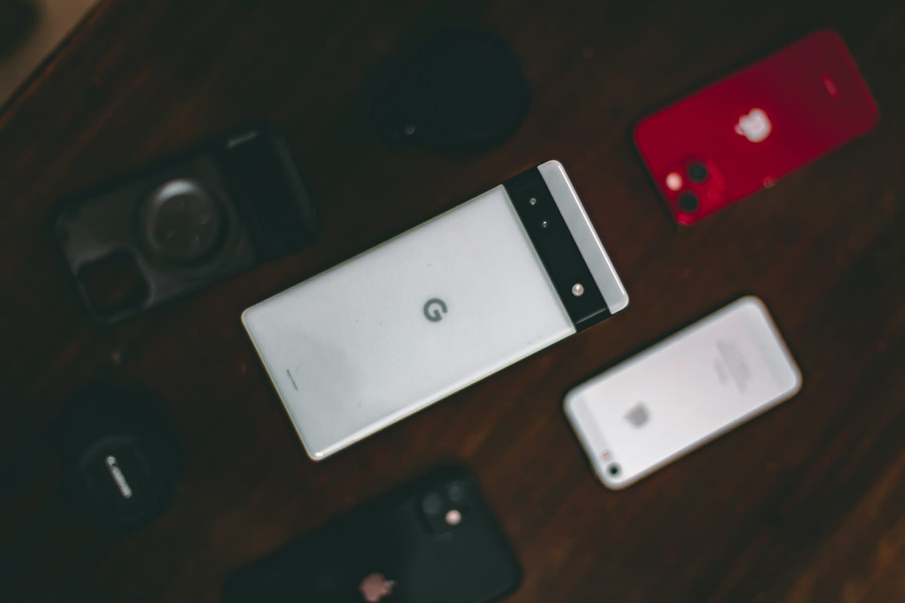 Several company smartphones laid out on a wooden table