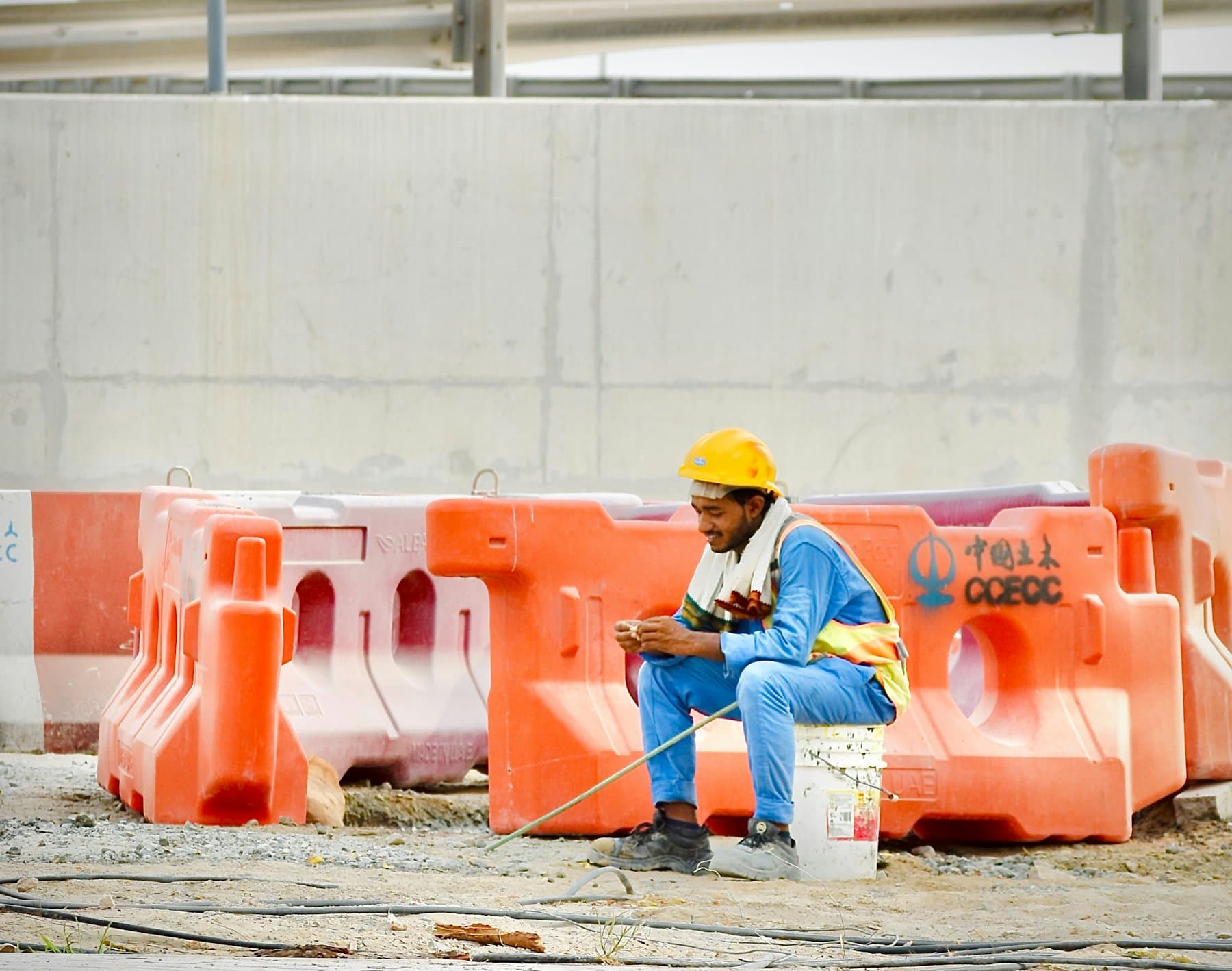 A construction worker in a hard hat sitting and using a phone on site