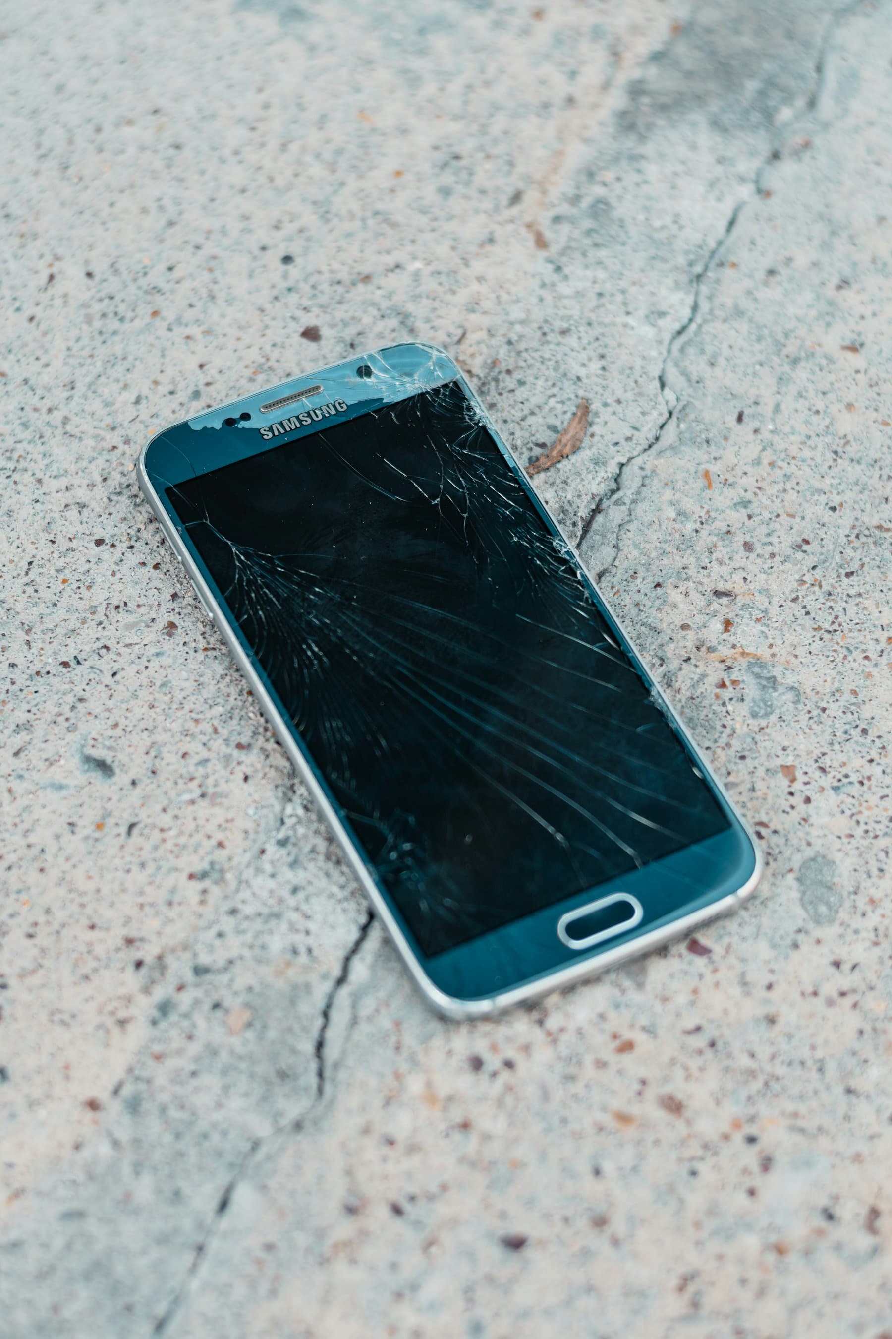 A smartphone lying face down on a concrete floor