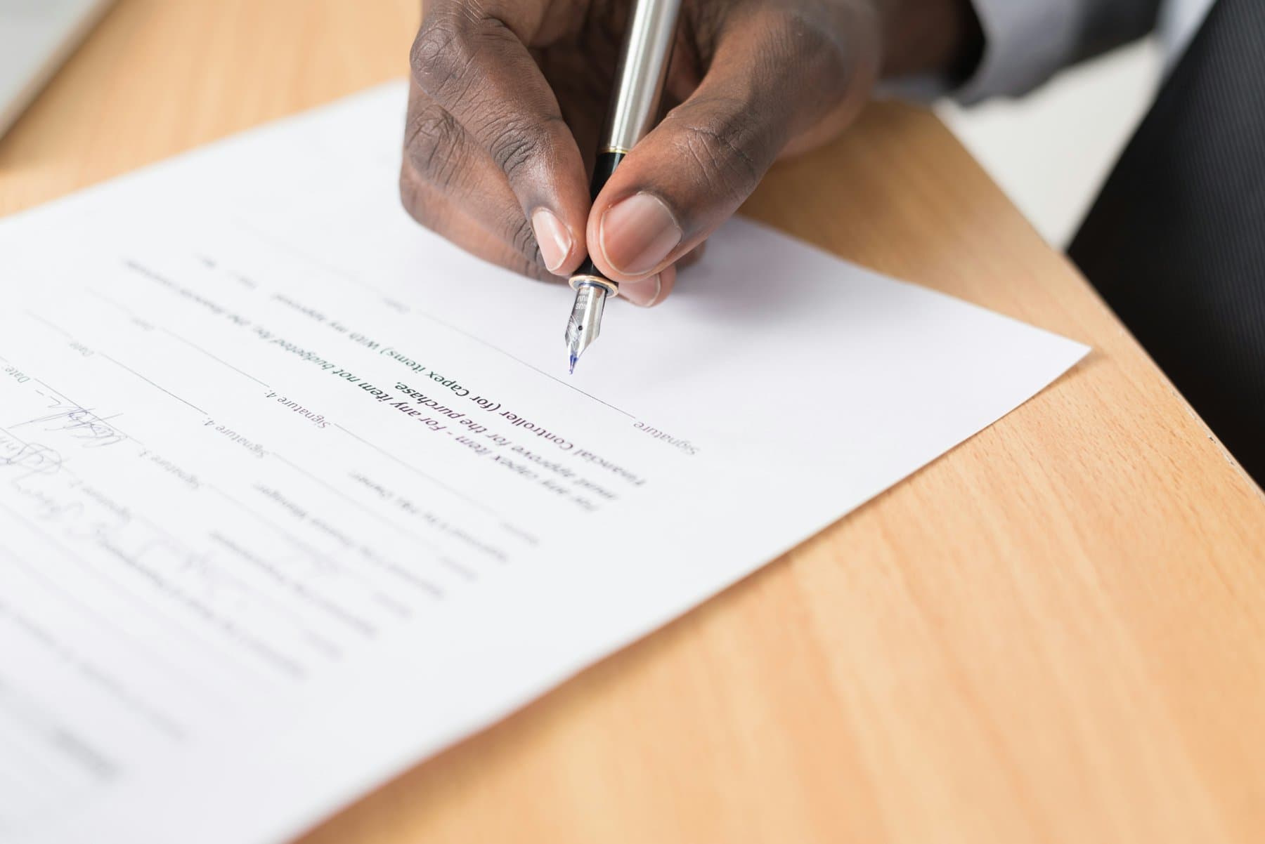 A person writing on a printed document at a desk
