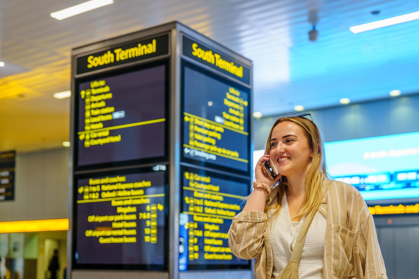 A traveller on a phone beside an airport departure board