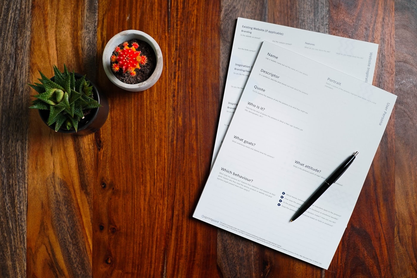 A wooden table with printed pages and a pen